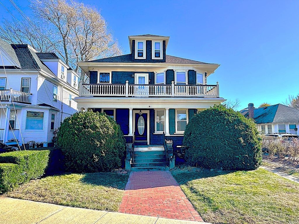 a front view of a house with a yard and potted plants