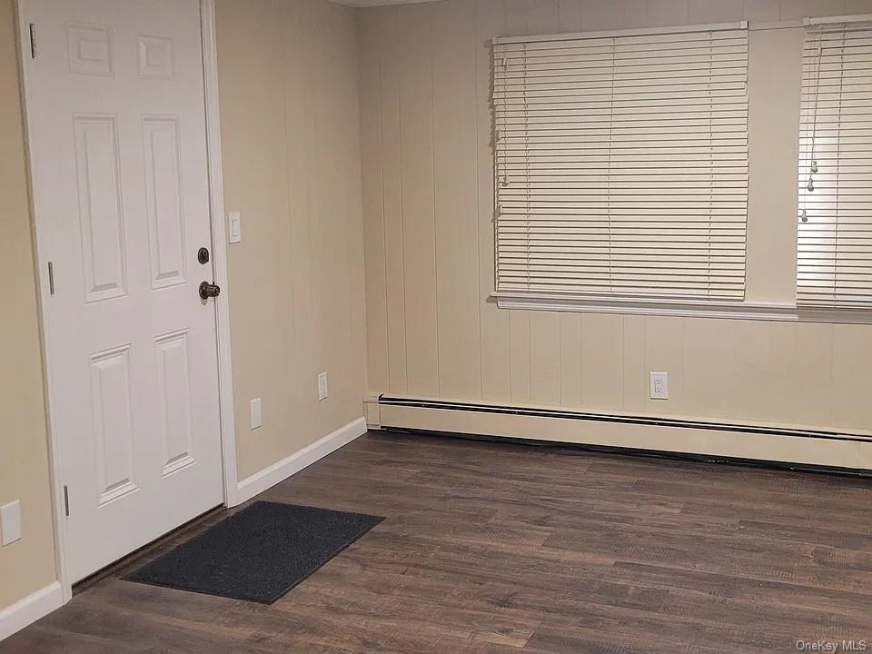 Empty room with a baseboard radiator and dark hardwood / wood-style floors