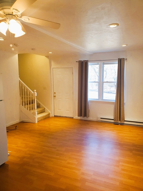 a view of an empty room with window and wooden floor