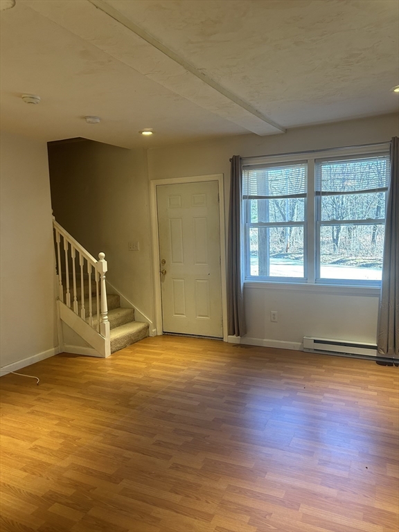 a view of an empty room with window and wooden floor