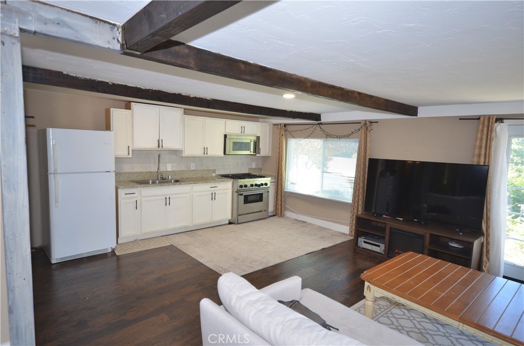 a living room with stainless steel appliances furniture and a flat screen tv