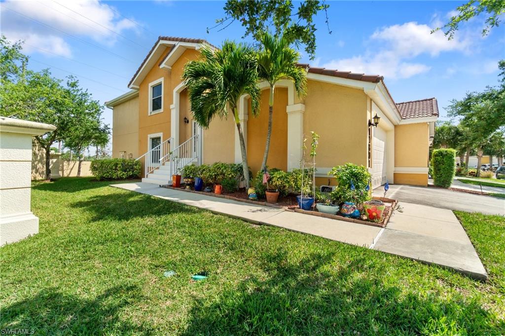 a front view of house and yard with beautiful flowers and green space