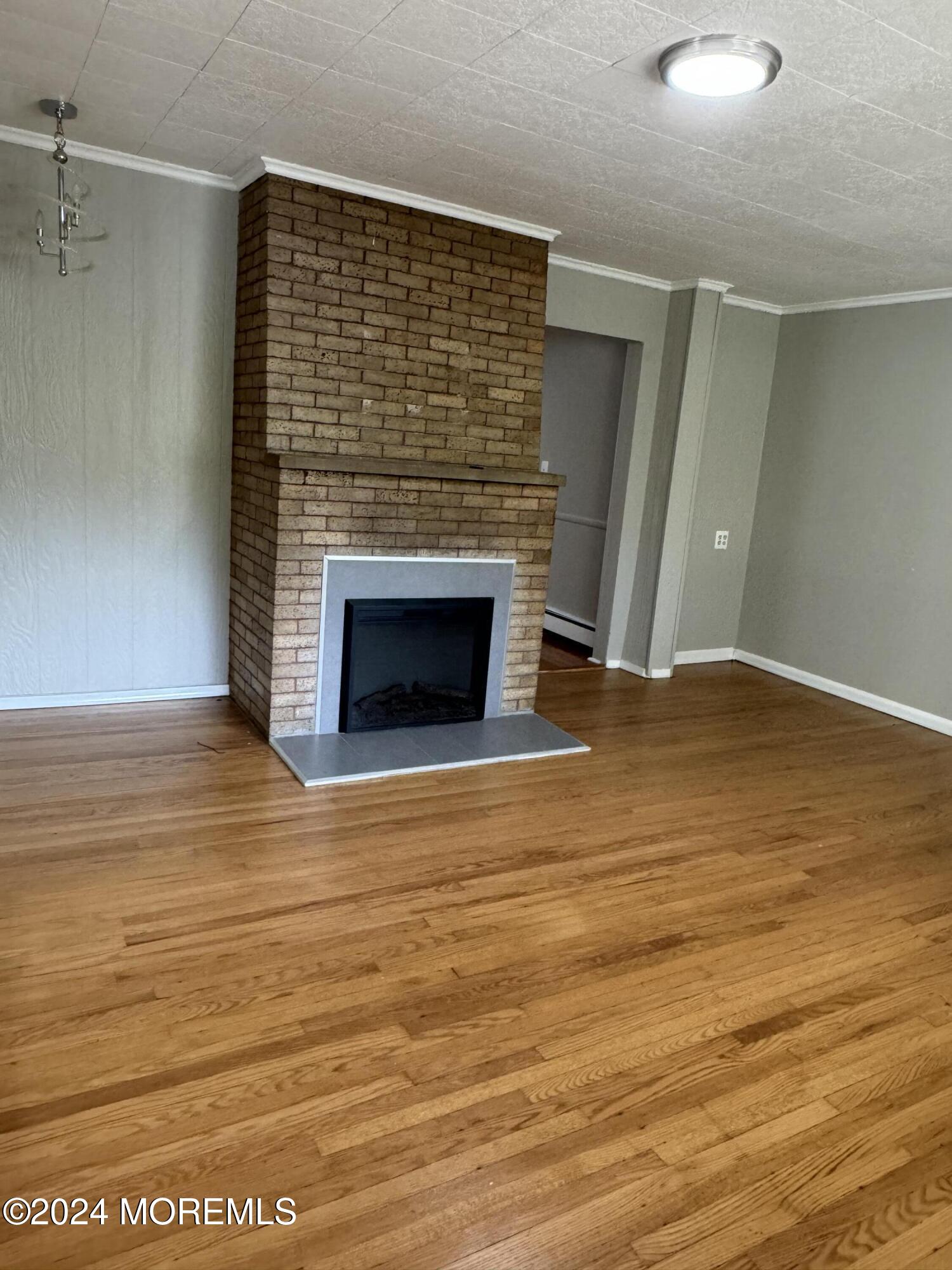 a view of empty room with wooden floor and fireplace