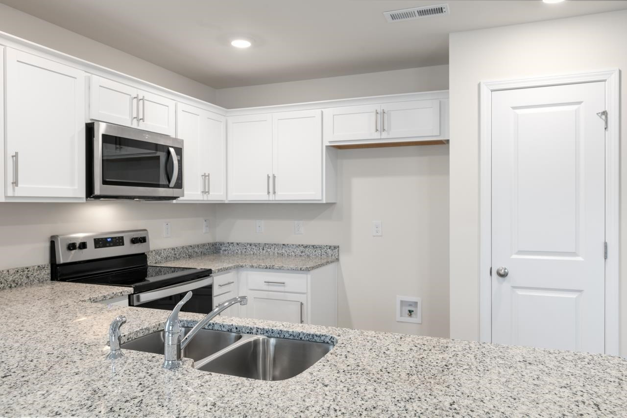 a kitchen with stainless steel appliances granite countertop a sink a stove a microwave and cabinets