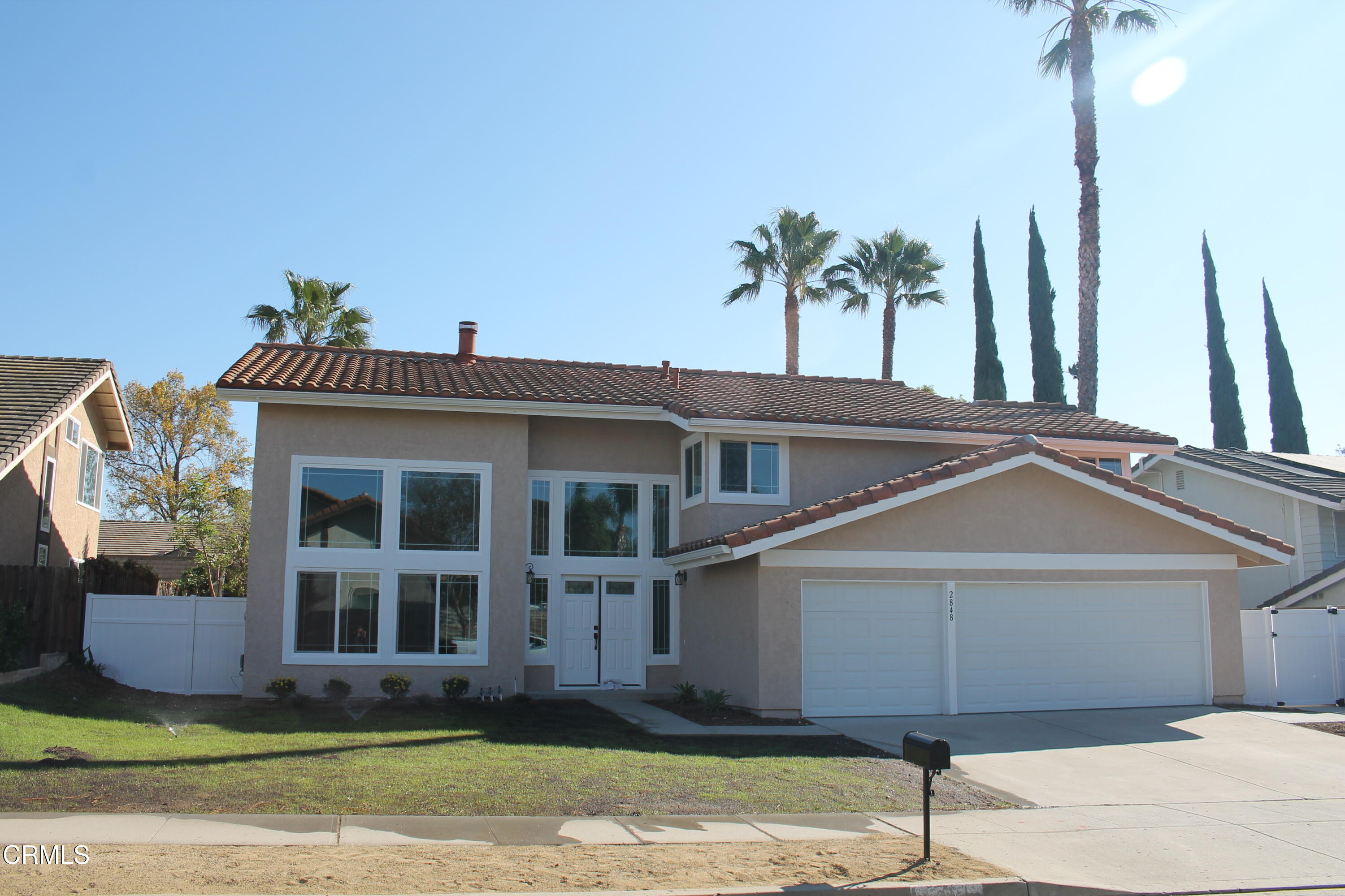 a front view of a house with a yard and potted plants