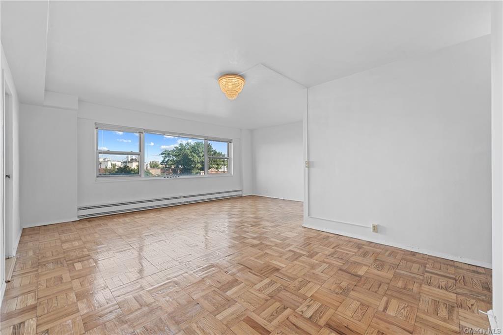 Spare room featuring a baseboard heating unit and light parquet floors