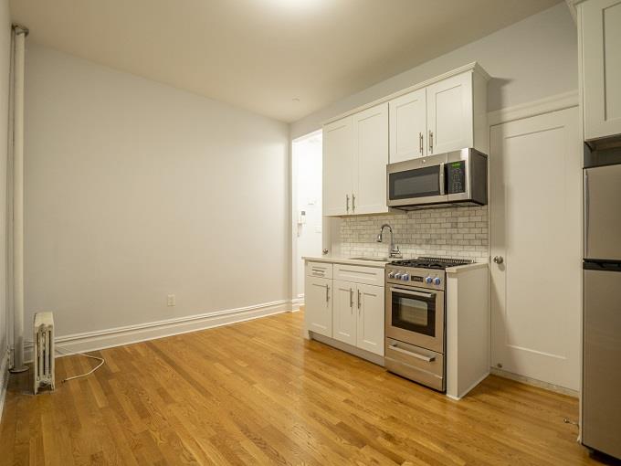 a kitchen with stainless steel appliances a stove a microwave and a hard wood floors