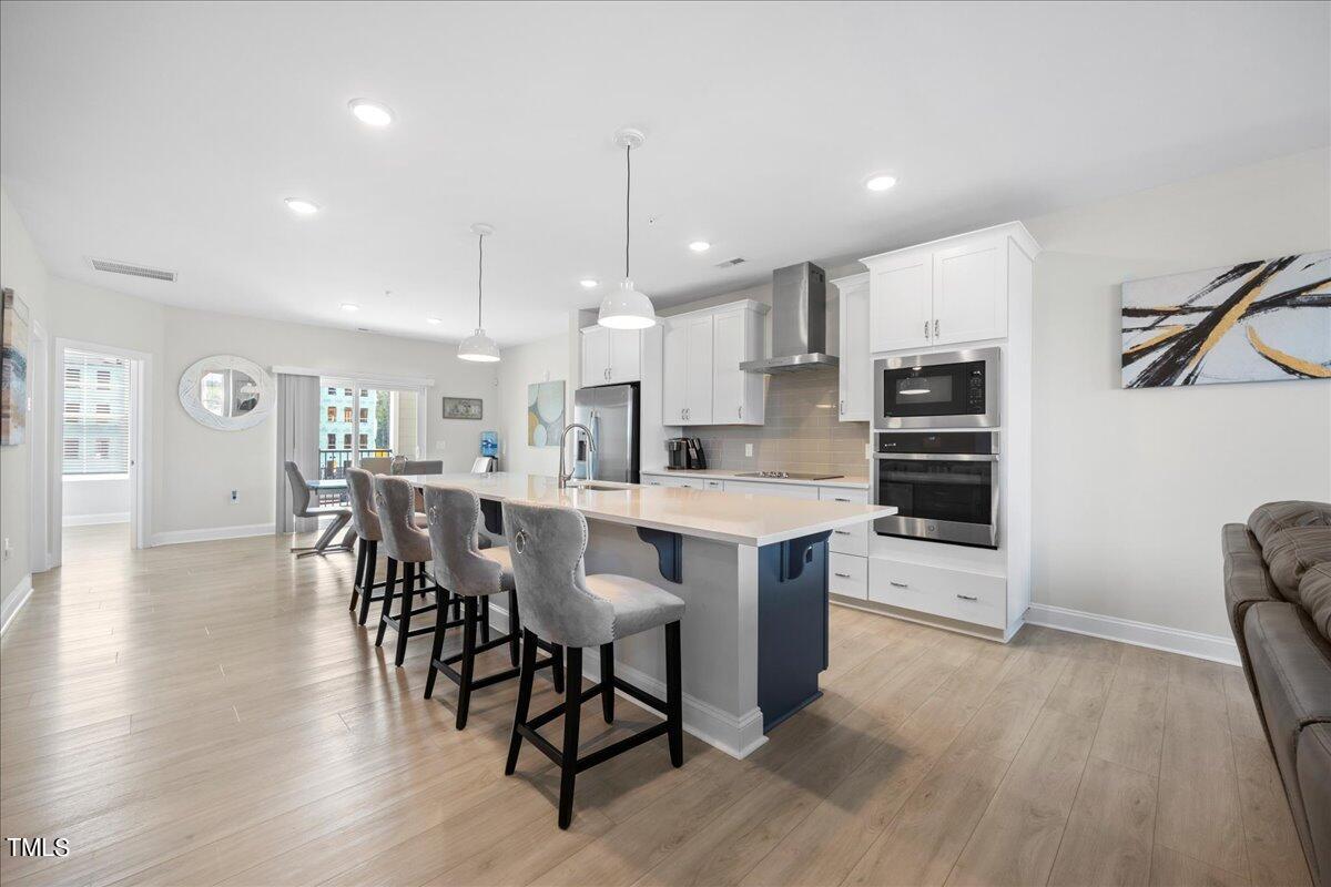 a kitchen with stainless steel appliances a dining table chairs refrigerator and sink