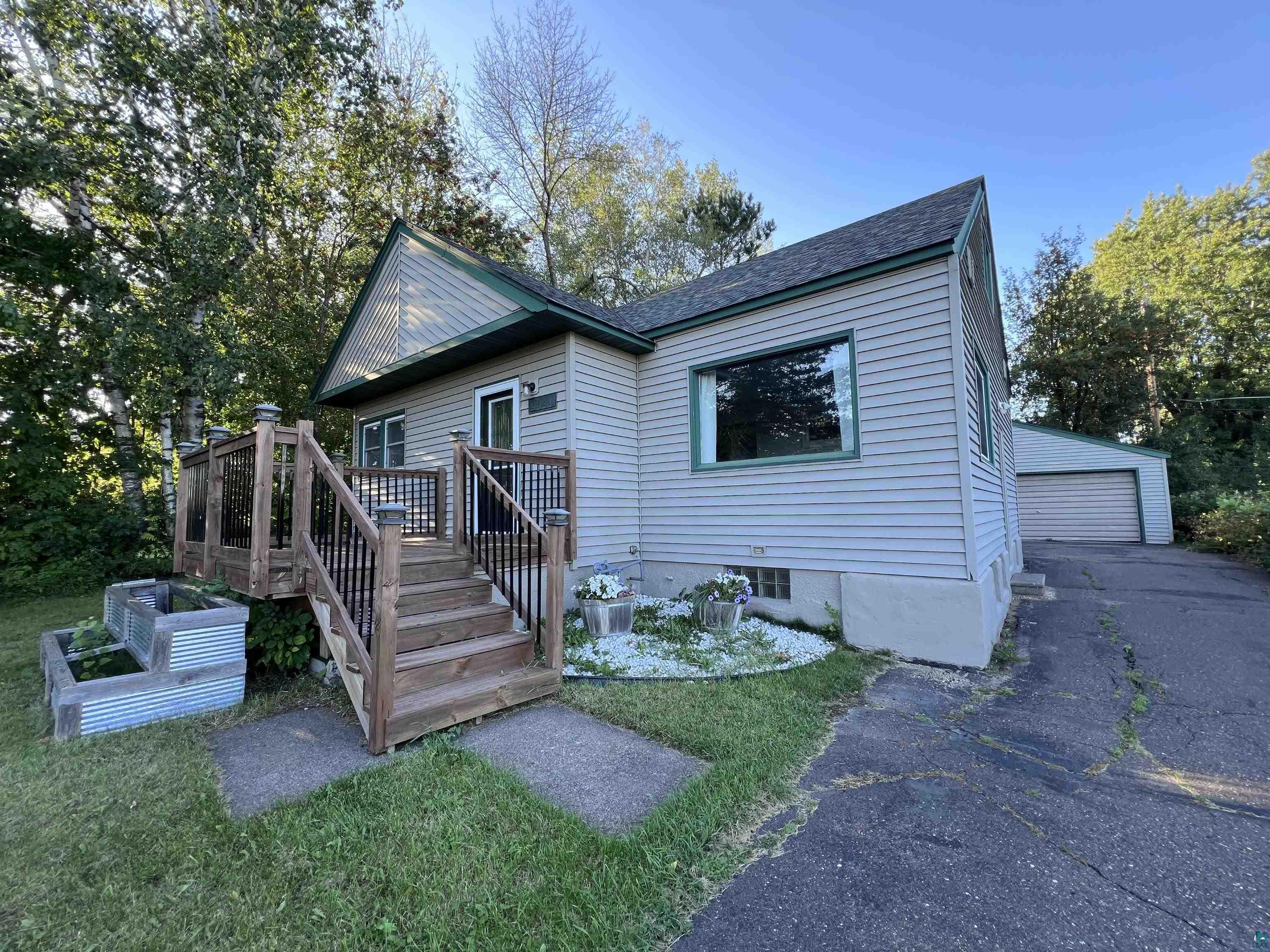 View of front of home featuring a front yard, a garage, an outdoor structure, and a wooden deck