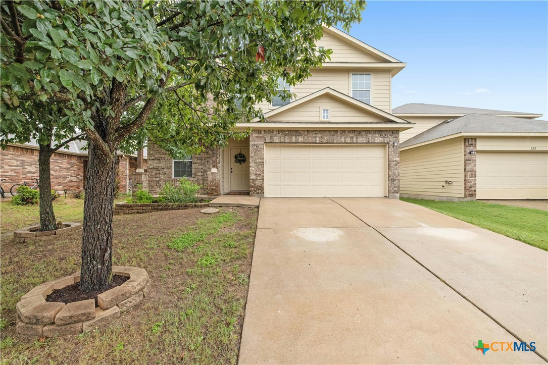 a view of a house with a yard and large tree