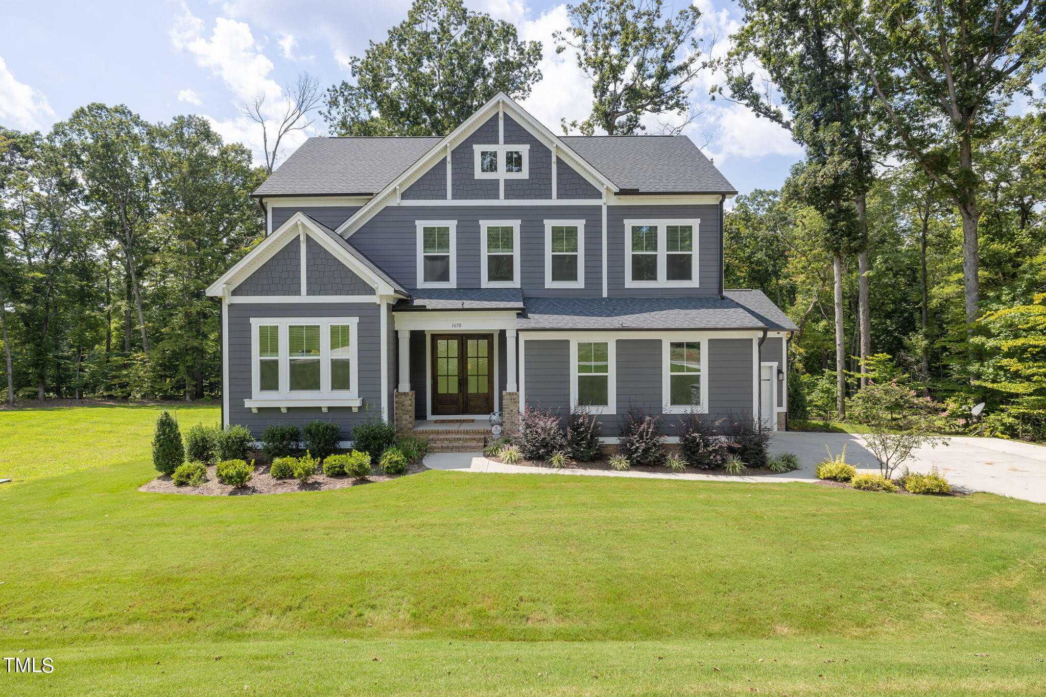 a front view of a house with a garden and trees