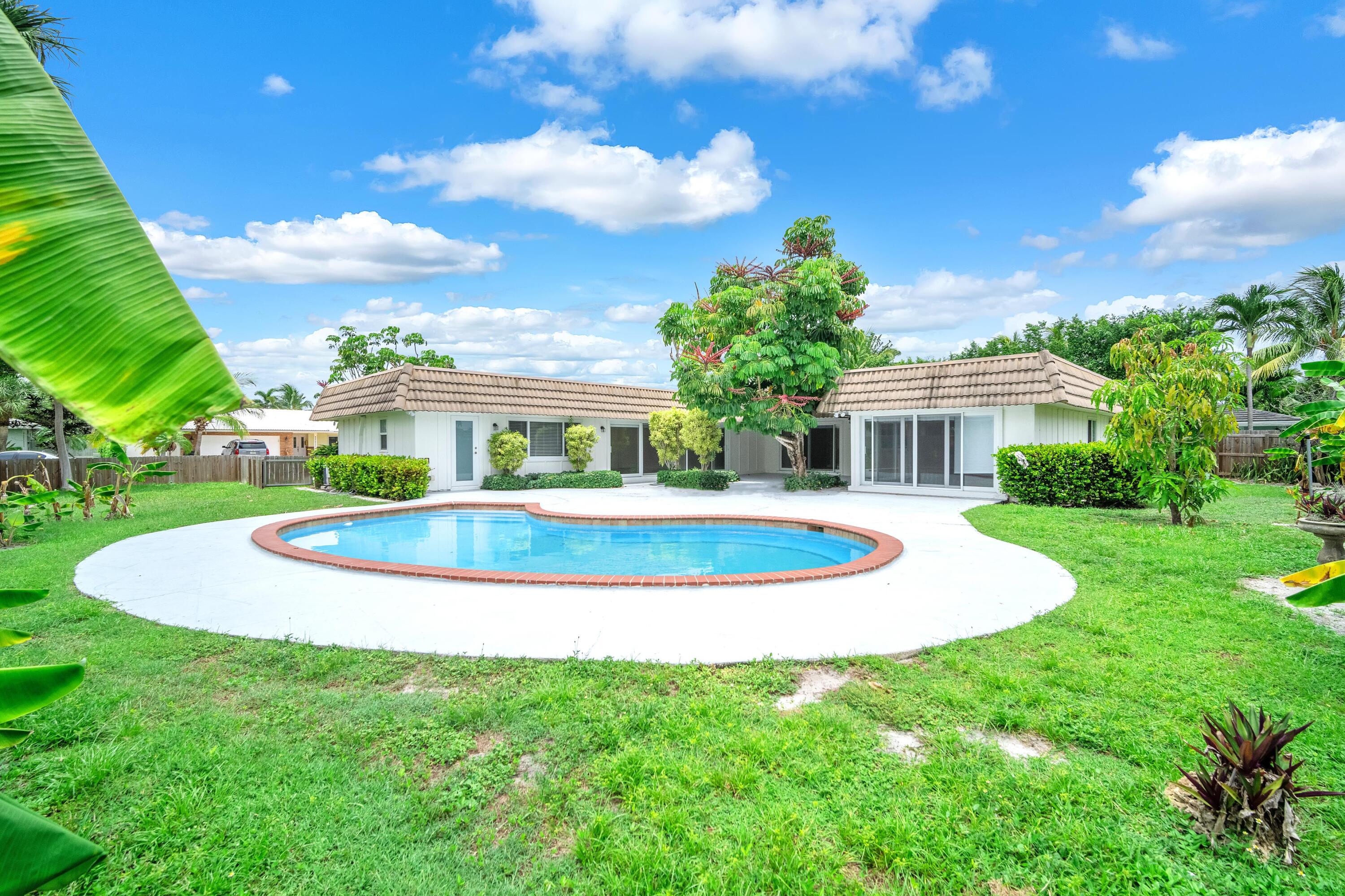 a view of a white house with a swimming pool and a yard