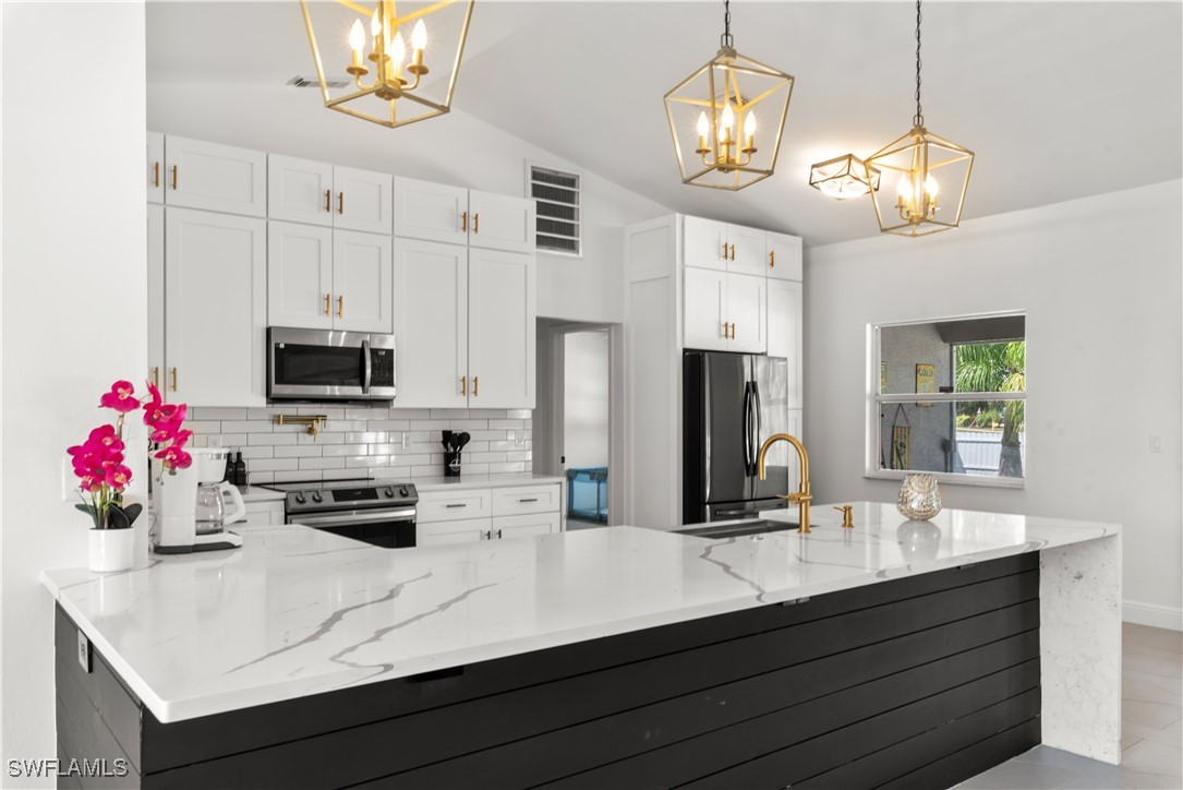 a kitchen with kitchen island white cabinets and stainless steel appliances