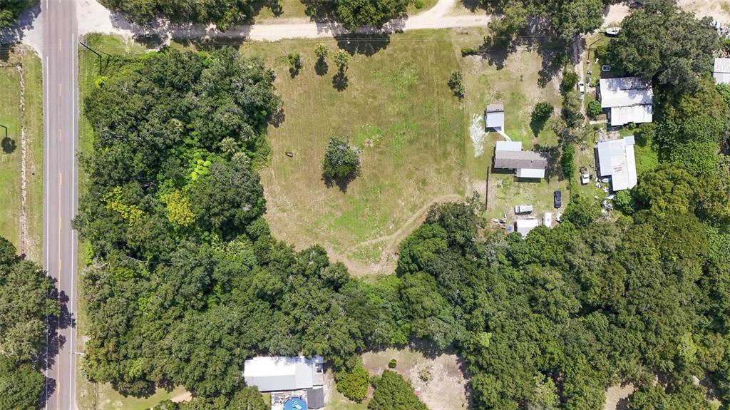 an aerial view of residential house with outdoor space and trees all around