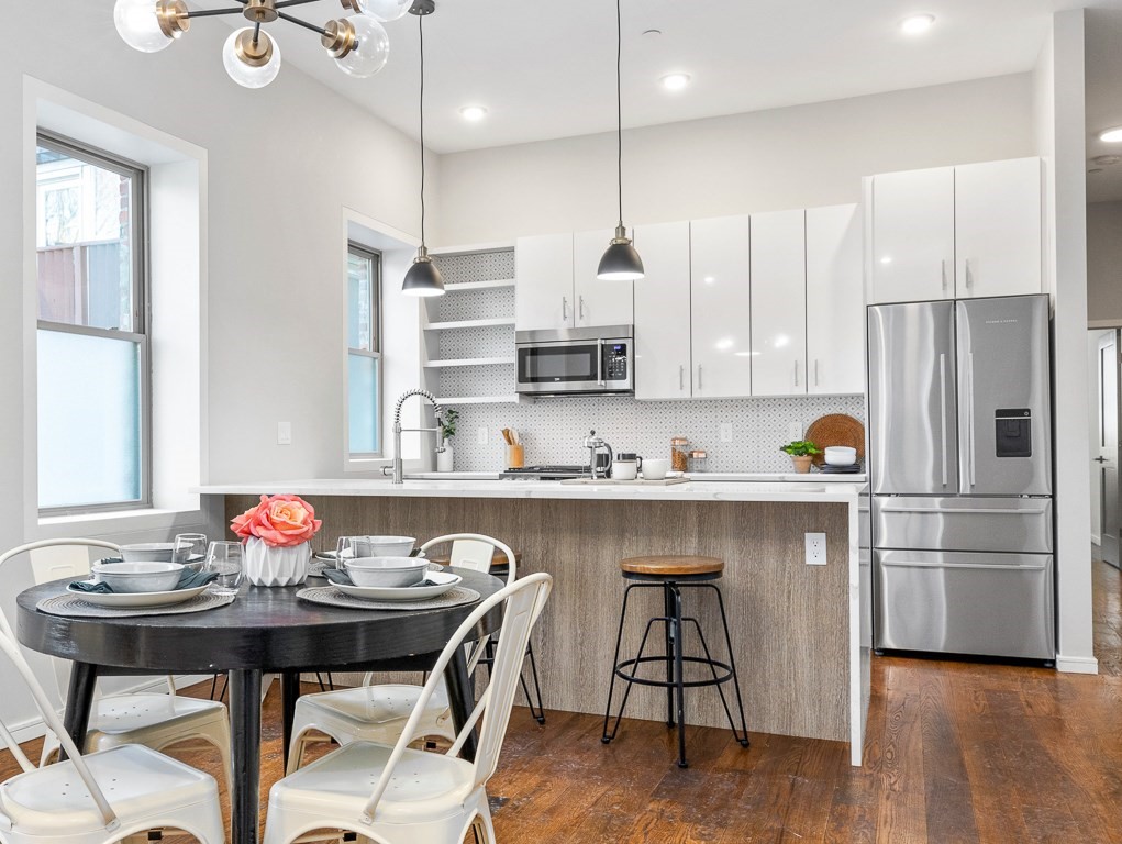 a kitchen with stainless steel appliances granite countertop a table chairs stove and kitchen island