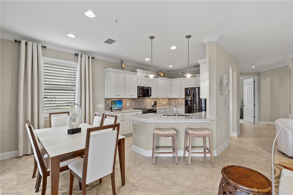 a kitchen with kitchen island a dining table chairs stainless steel appliances and cabinets