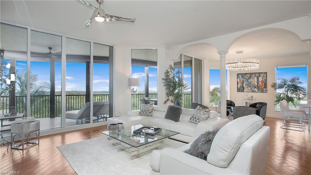 a living room with furniture large window and wooden floor