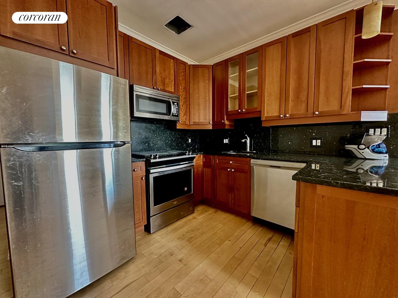 a kitchen with stainless steel appliances granite countertop a refrigerator a sink dishwasher a stove top oven a refrigerator and cabinets with wooden floor