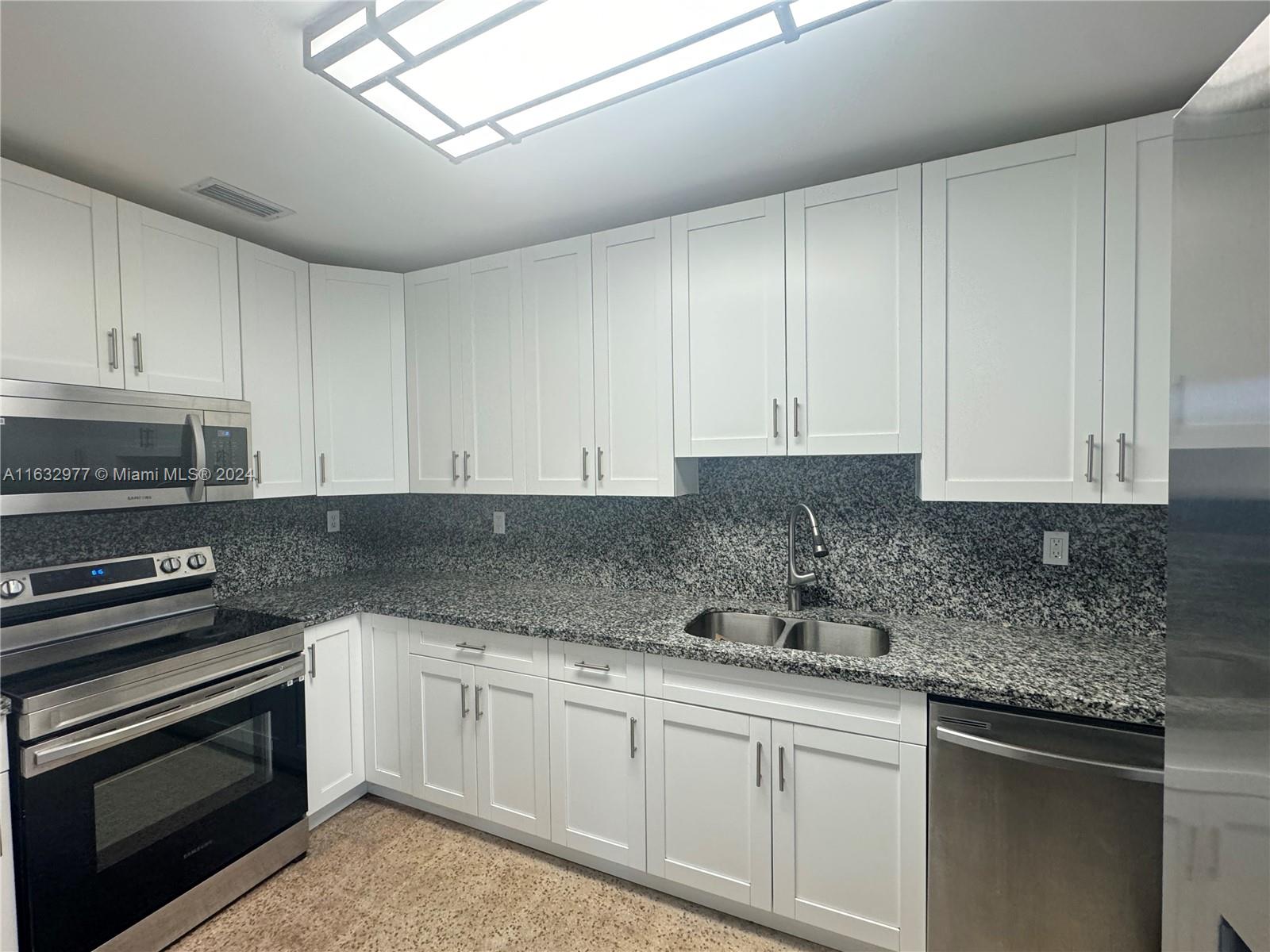 a kitchen with granite countertop white cabinets and stainless steel appliances