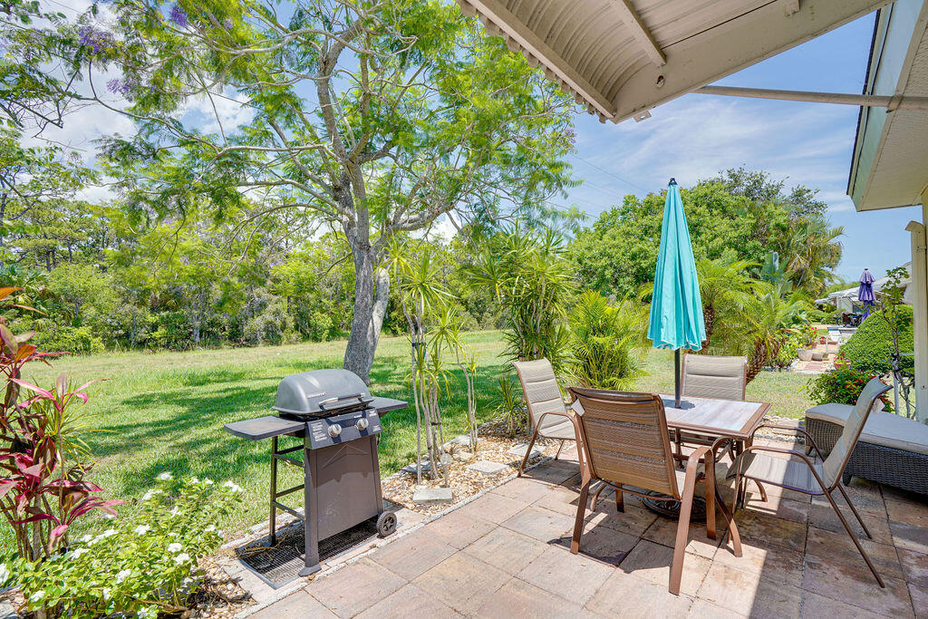 a view of a backyard with table and chairs potted plants and large tree