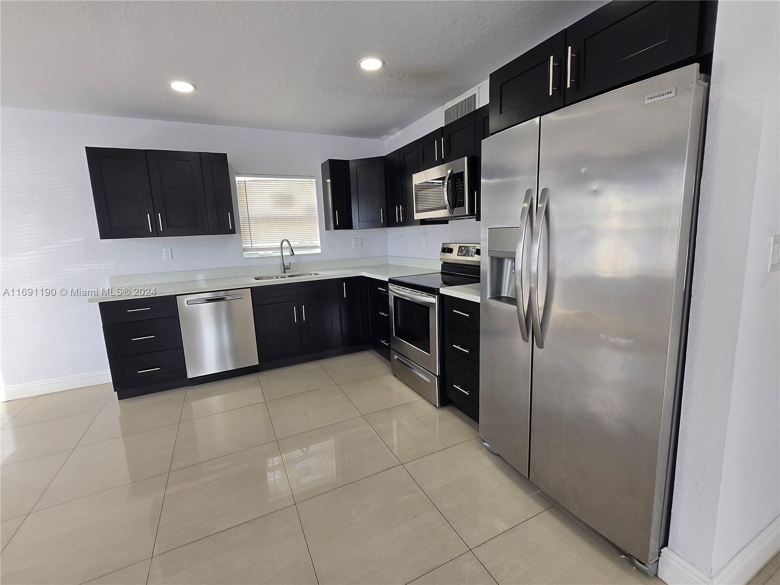 a large kitchen with stainless steel appliances granite countertop a refrigerator and a sink