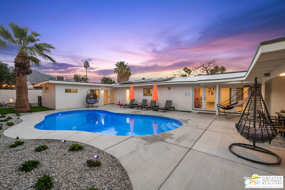 a view of a house with backyard swimming pool and sitting area