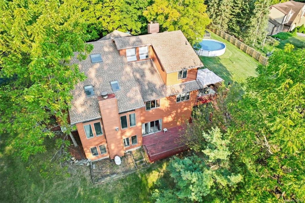 an aerial view of residential house with outdoor space and trees all around