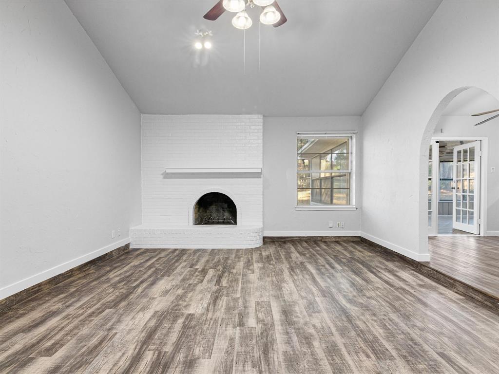 an empty room with windows and fireplace