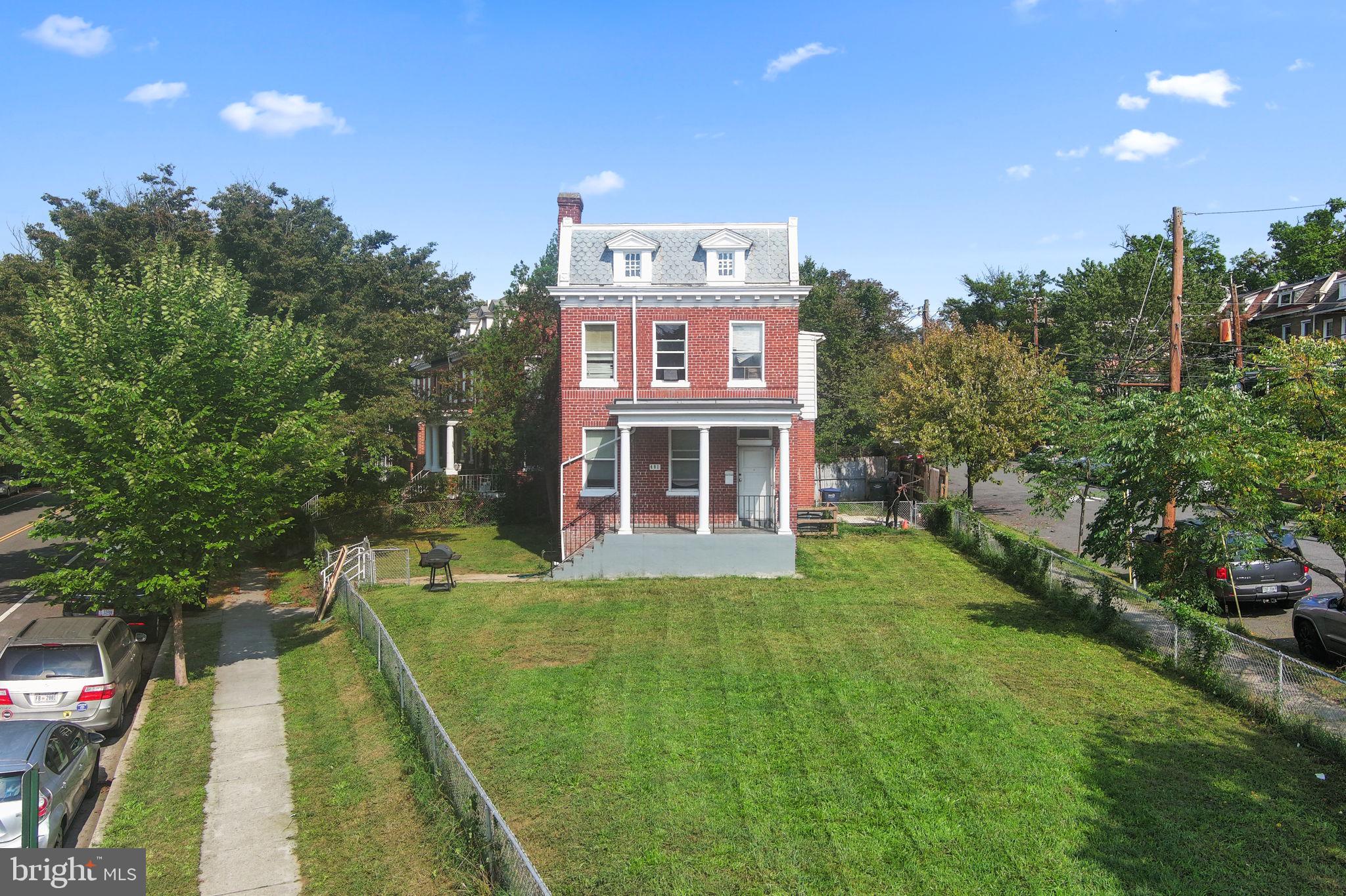 a view of a house with a big yard plants and large trees