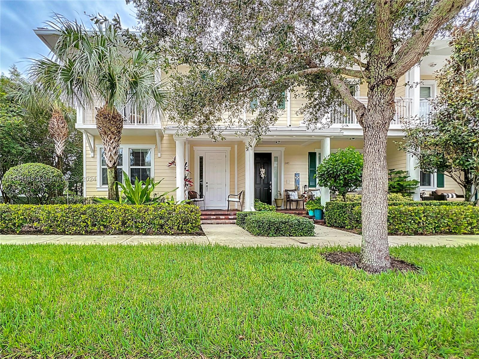 a front view of a house with a yard and potted plants