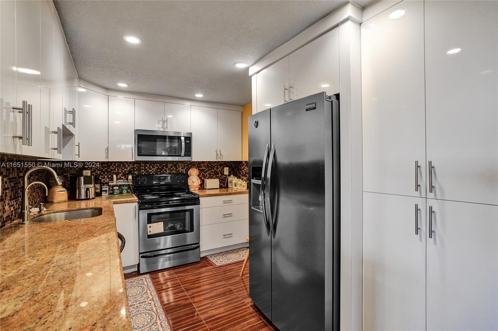 a kitchen with stainless steel appliances granite countertop a refrigerator and a sink