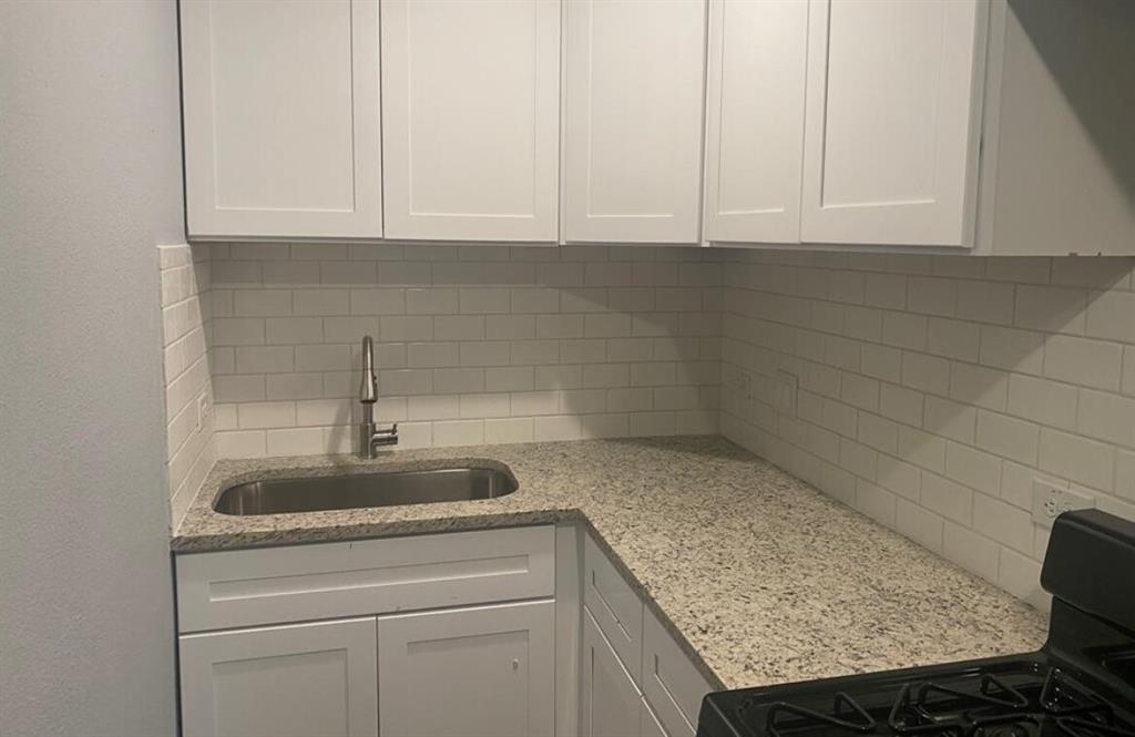 a kitchen with granite countertop white cabinets and a sink