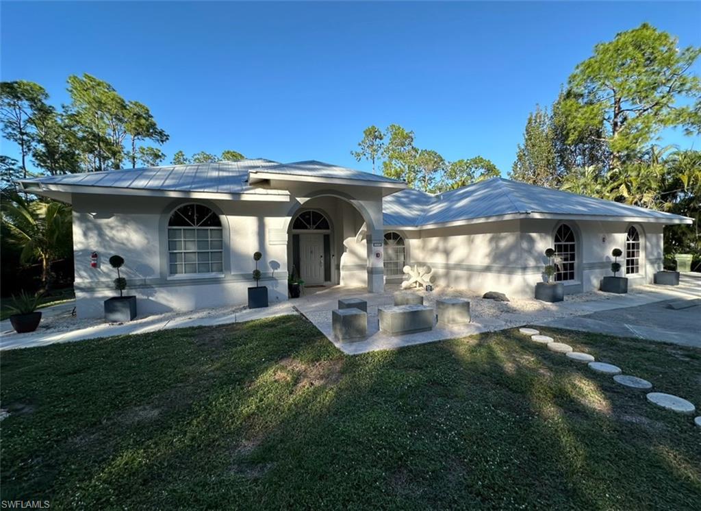 Rear view of house featuring solar panels, a patio area, and a yard