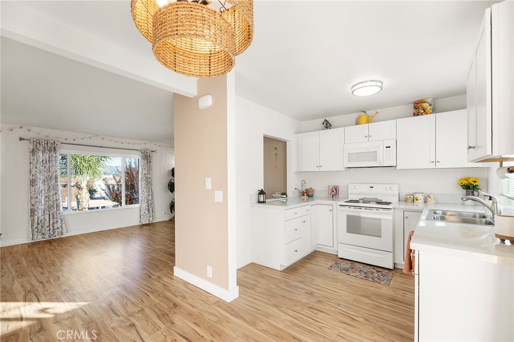 a kitchen with granite countertop a white stove top oven and white cabinets with wooden floor