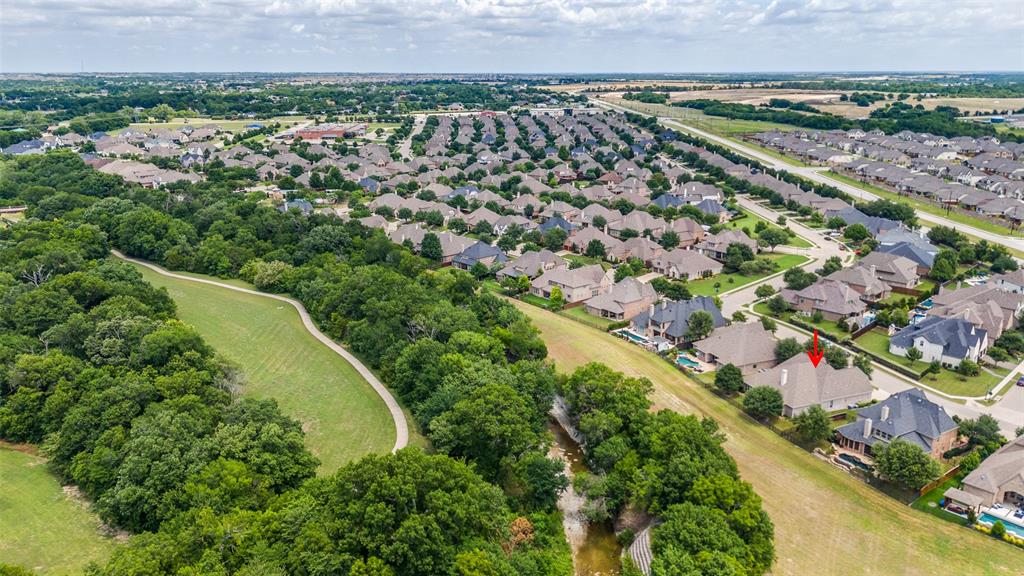 an aerial view of a residential houses with outdoor space and trees