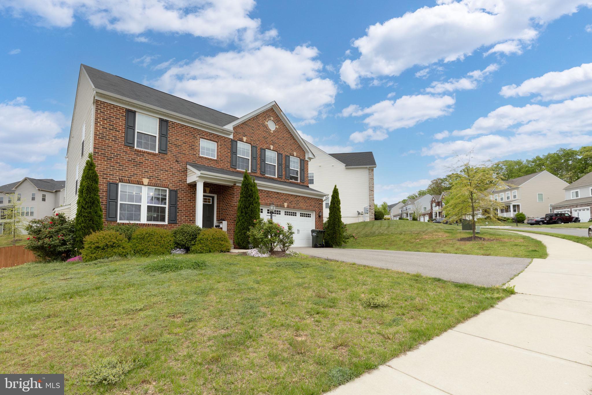 a view of a big yard in front of a brick house with large windows