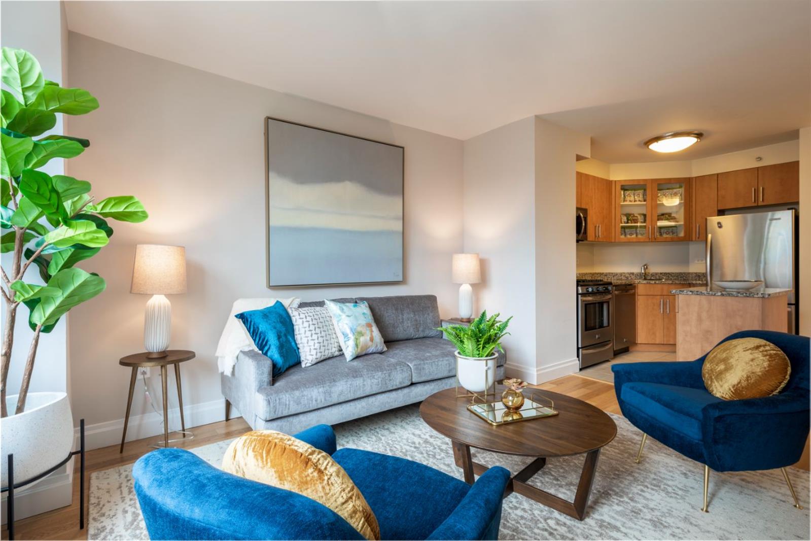 a living room with furniture potted plant and kitchen view