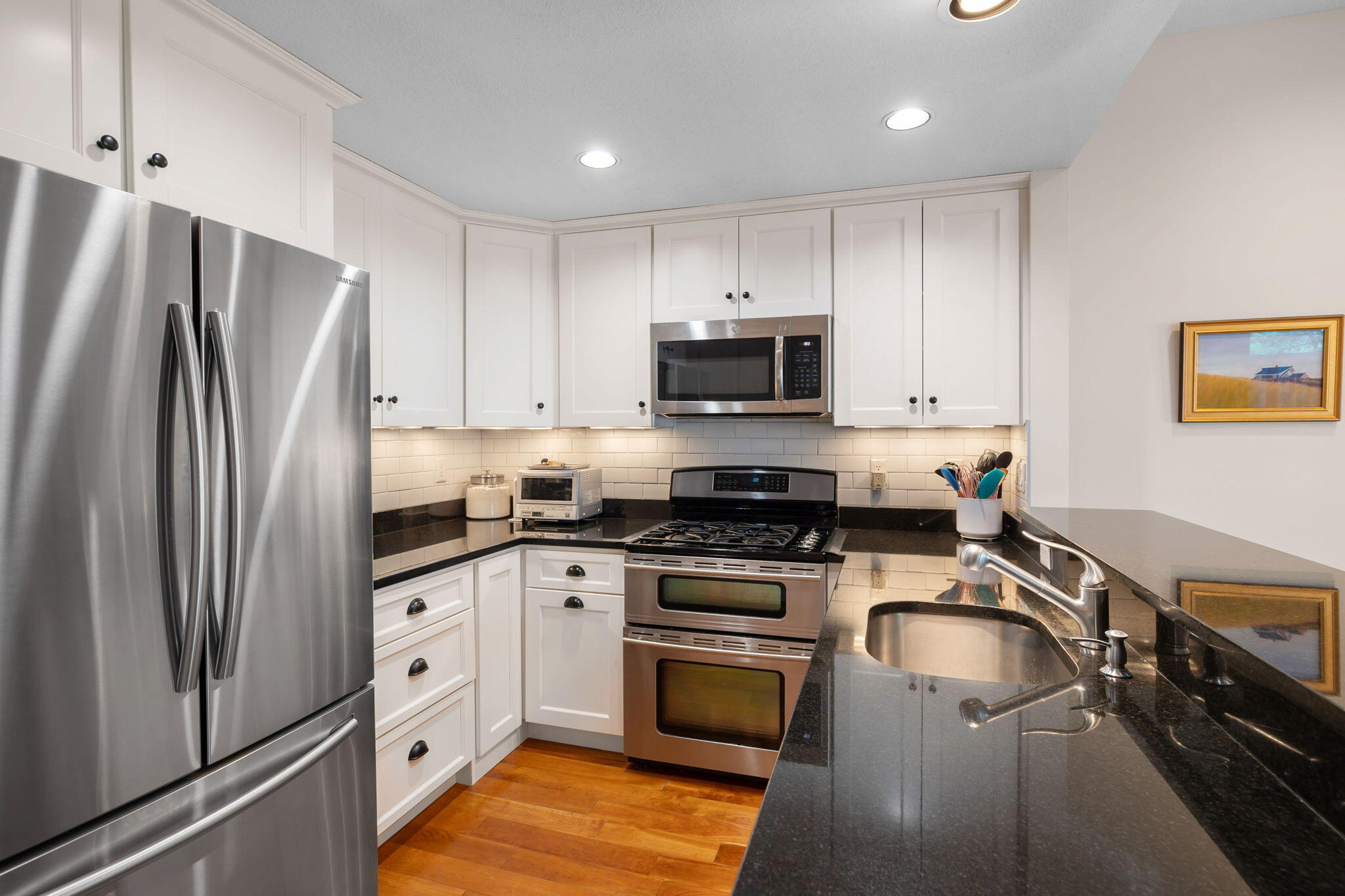 a kitchen with granite countertop a refrigerator stove and sink