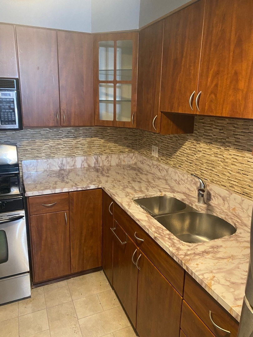 a kitchen with granite countertop a sink dishwasher stove and cabinets