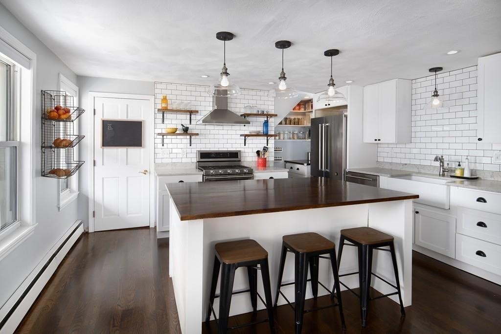 a kitchen with stainless steel appliances kitchen island granite countertop a table chairs and a refrigerator