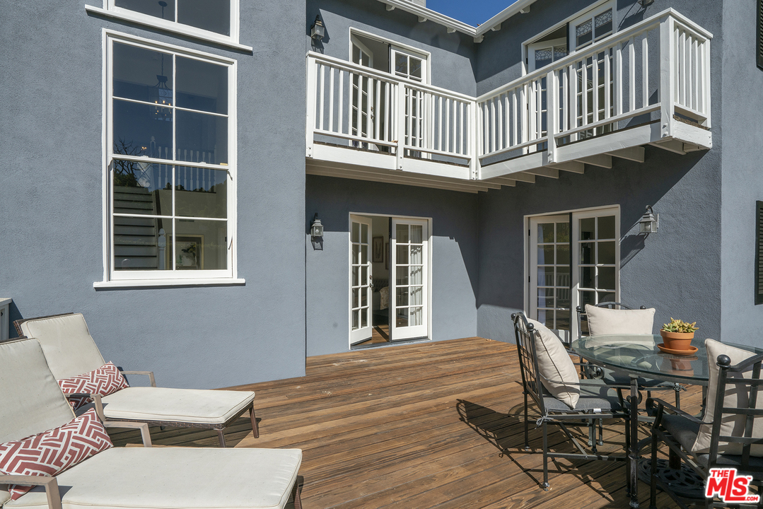 a balcony with table and chairs and wooden fence