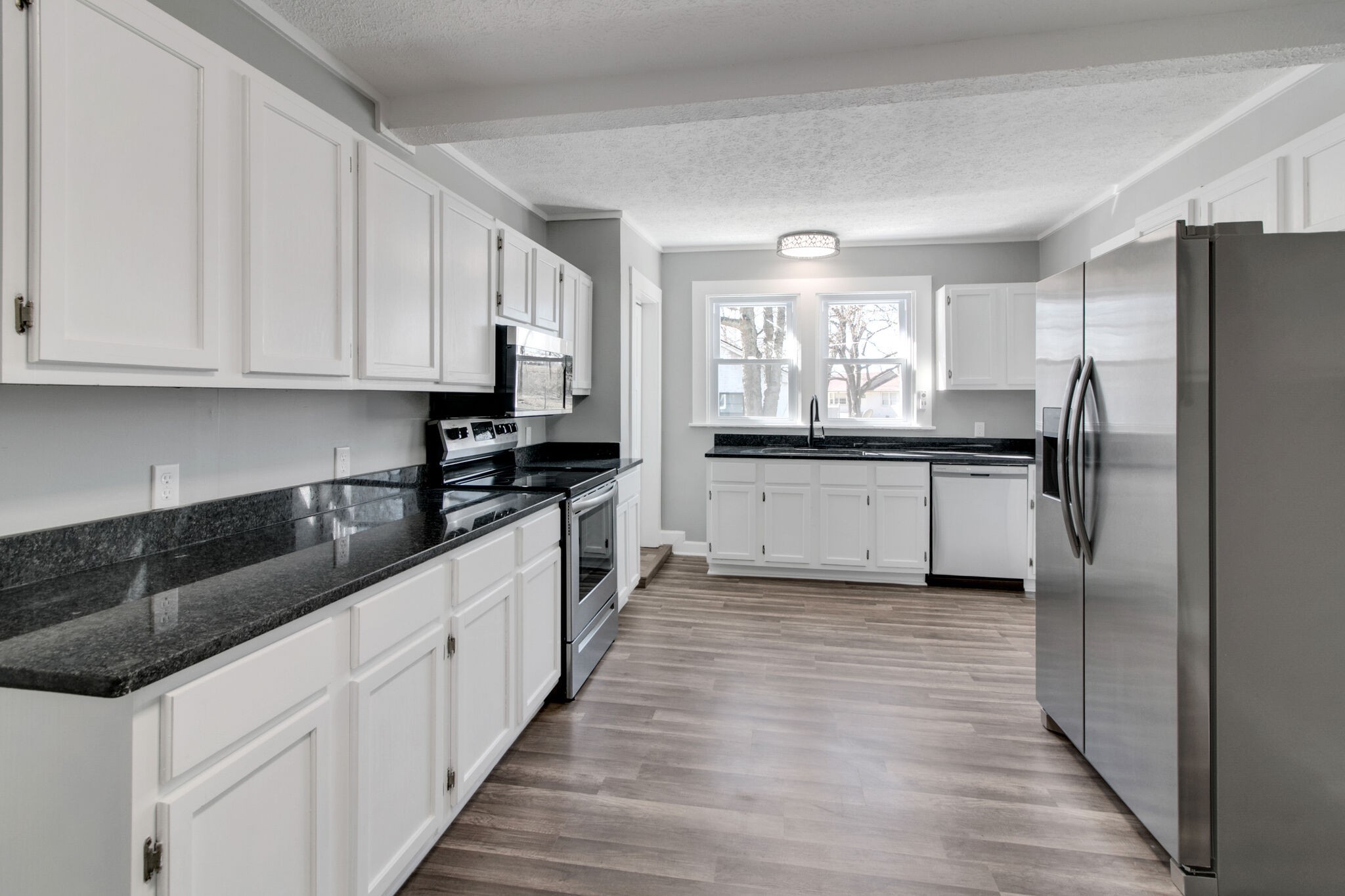 a kitchen with granite countertop a refrigerator and a sink