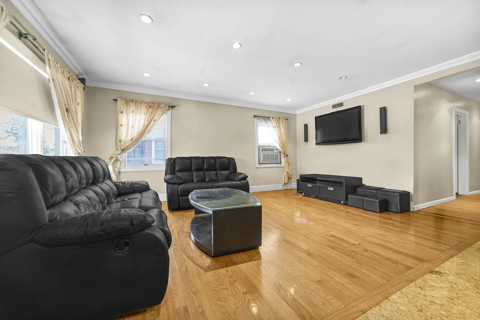 Living room with cooling unit, wood-type flooring, and crown molding