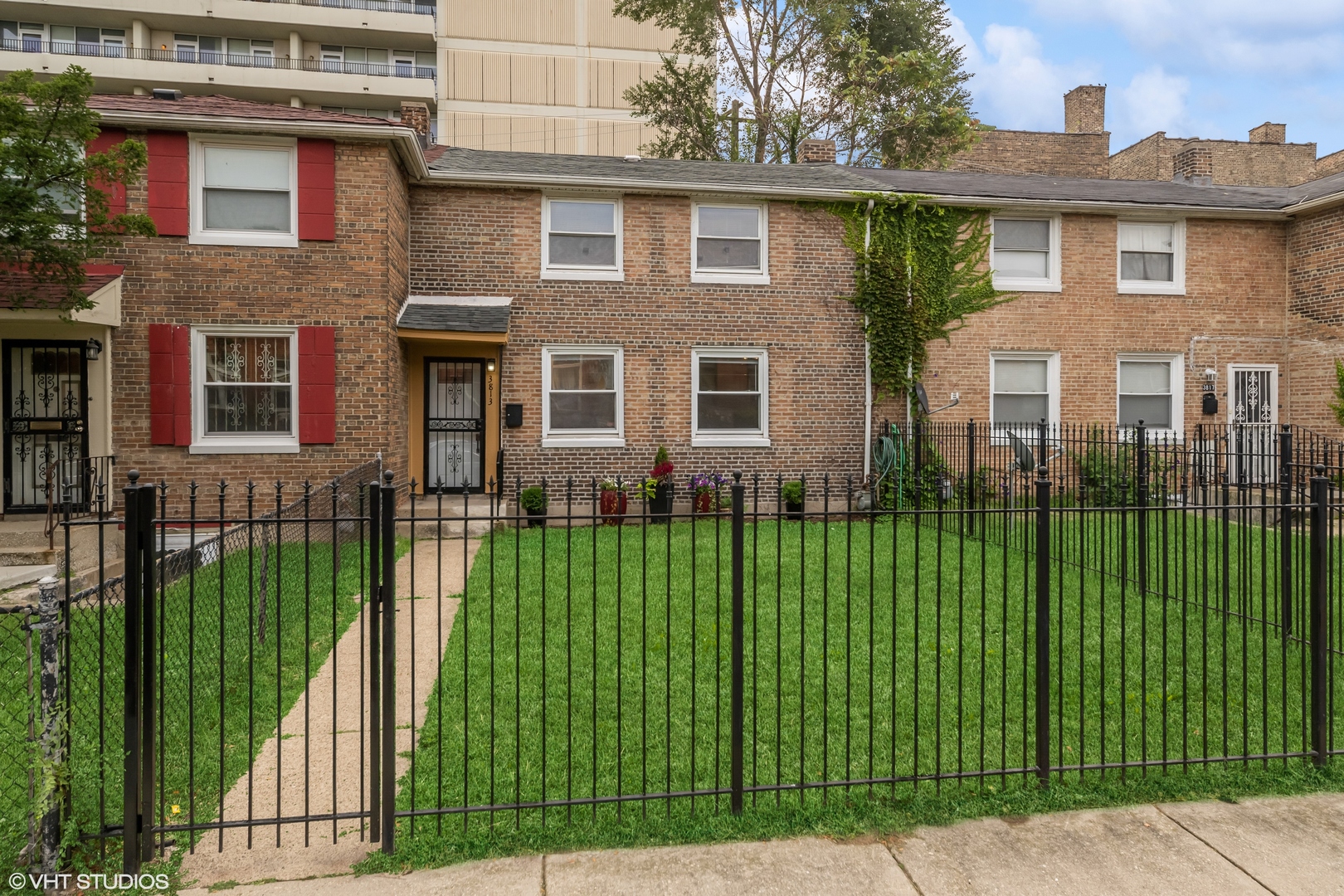 a view of a brick house with a big yard and plants