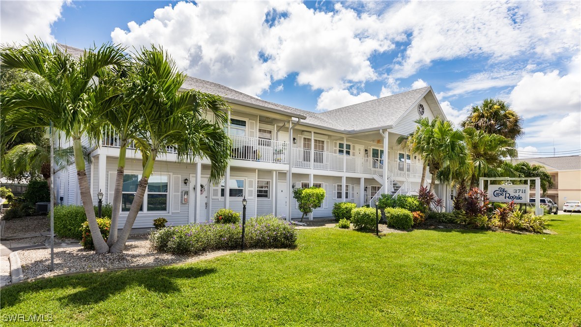 a view of a house with a big yard plants and palm trees