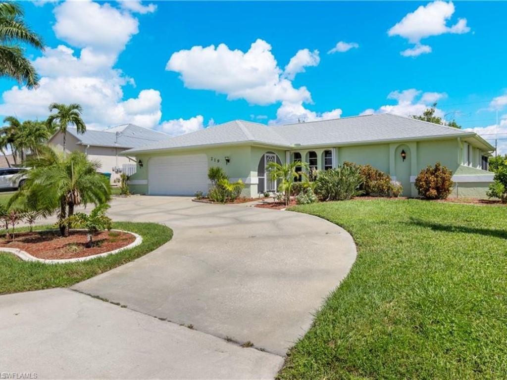 Single story home with a garage and a front lawn