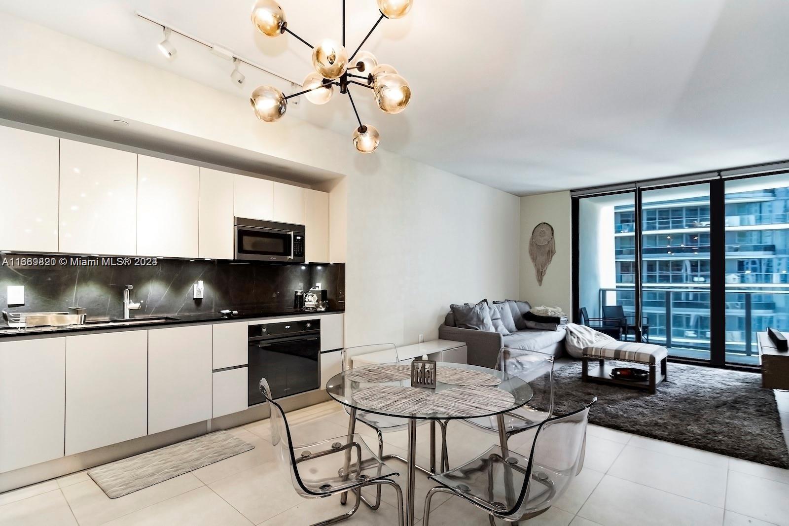 a kitchen with stainless steel appliances kitchen island granite countertop a table chairs and a refrigerator