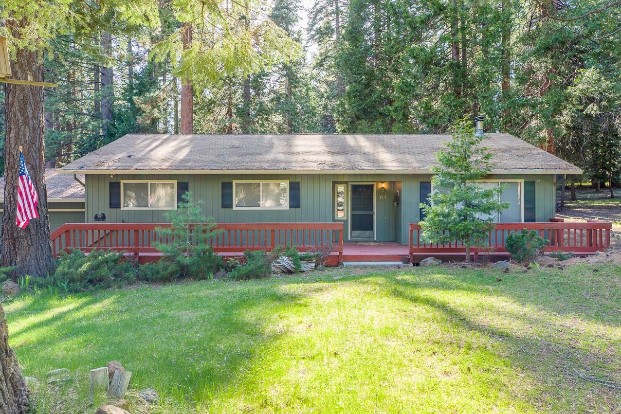 a front view of a house with a garden and trees