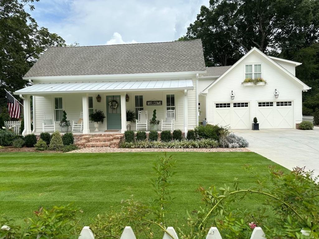 a view of a white house with a big yard and potted plants