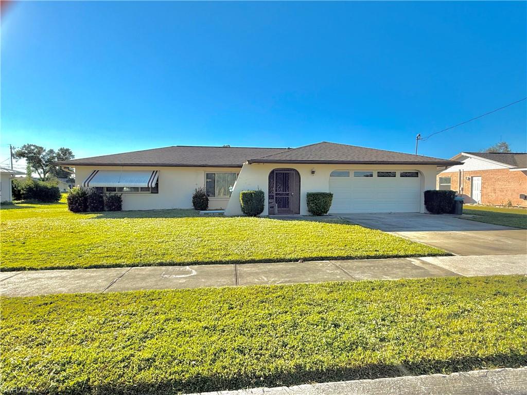 Ranch-style home featuring a garage and a front lawn